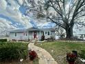 Inviting single-story home featuring mature trees, charming front porch, and a lush lawn leading to the lake at 1050 E Eagle Ave, Eagle Lake, FL 33839