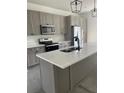 Modern kitchen boasts stainless steel appliances, gray cabinetry, quartz countertops, and an island with a sink at 1205 Lake Loop Rd, Winter Haven, FL 33880