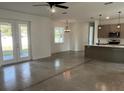 Bright living room area featuring sleek flooring, gray walls, modern lighting, and a view into the adjacent kitchen at 1205 Lake Loop Rd, Winter Haven, FL 33880