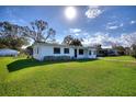 Well-maintained single-story home featuring a lush green lawn and mature trees under a sunny sky at 1229 Rawls Dr, Lakeland, FL 33801