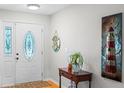 Bright foyer featuring a decorative front door with sidelights, wood floors, and charming decor at 128 Lake Ring Dr, Winter Haven, FL 33884