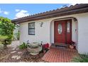 Inviting front entrance with a decorative red door, brick pathway, and lush landscaping at 128 Lake Ring Dr, Winter Haven, FL 33884