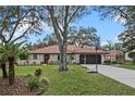 Charming home with a red-tiled roof, mature trees, green lawn, and a long driveway at 128 Lake Ring Dr, Winter Haven, FL 33884