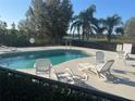 Community pool area with chaise lounges, chairs, palm trees, and lake views, perfect for relaxation at 2673 Rutledge Ct, Winter Haven, FL 33884