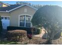 Charming home featuring a large arched window, attached garage and mature, manicured landscaping at 2673 Rutledge Ct, Winter Haven, FL 33884