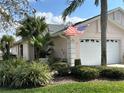 Beautiful home with lush landscaping, a two-car garage, and an American flag waving gently at 37 Enclave Dr, Winter Haven, FL 33884