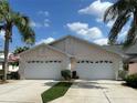 Charming home featuring a two-car garage, well-manicured lawn, tropical landscaping, and an American flag at 37 Enclave Dr, Winter Haven, FL 33884