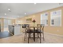 Bright dining area with a round table and chairs, adjacent to kitchen island seating, lit by two windows at 3821 Giorgio Dr, Winter Haven, FL 33884