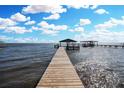 Long, wooden dock leading to covered boat slips on the serene water under a blue sky at 3943 Chambers St, Lake Wales, FL 33898
