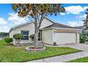 Well-maintained front yard with mature trees, stone-lined flower beds, and brick driveway leading to the two-car garage at 496 Lake Suzanne Dr, Lake Wales, FL 33859