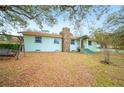 Charming front exterior view showcasing the stone chimney and mature trees at 660 Duggers Way, Lake Wales, FL 33859