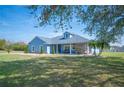 Inviting single-story home with blue exterior, stone accents, and mature trees at 9461 Redhawk Bend Ln, Lakeland, FL 33810