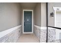 Exterior shot of a home's front door, framed by stone accents and modern lighting at 153 Summershore Dr, Auburndale, FL 33823