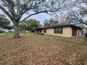 A single-story brick home with an attached garage, surrounded by lush greenery and mature trees at 2016 Amesbury Dr, Auburndale, FL 33823