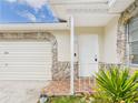 Close-up of the front entrance featuring a white door, stone accents, and tiled porch at 2434 Mill Run Blvd, Kissimmee, FL 34744