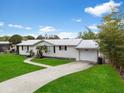 A well-maintained single-story home showcasing a white exterior, lovely landscaping, and an attached garage at 4024 Canal Rd, Lake Wales, FL 33898