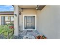 Close-up of a gray front door with sidelights and a brick paver walkway at 4814 Summit View Way, Auburndale, FL 33823