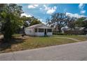 A one-story home with a screen front porch, nestled among mature trees, and a well-maintained lawn at 750 Avenue O Sw, Winter Haven, FL 33880