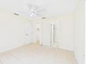 Bright bedroom featuring neutral walls, tiled floor, ceiling fan, and closet doors at 91 W Cedarwood Cir, Kissimmee, FL 34743