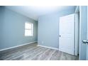 Comfortable bedroom with light blue walls, laminate floors, a window, and a white door at 1328 3Rd Ne St, Winter Haven, FL 33881