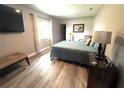 Cozy bedroom featuring wood floors, a queen bed, and a mounted television at 1442 Gilmore Ave, Lakeland, FL 33805