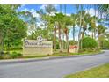 Welcoming 'Orchid Springs' sign surrounded by lush greenery and tall trees against a beautiful sunny sky at 200 El Camino Dr # 206, Winter Haven, FL 33884