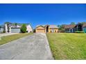 A charming single-story home with a two-car garage sits on a well-manicured lawn beneath a clear blue sky at 3430 Cove E Ct, Winter Haven, FL 33880