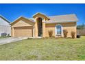 Inviting single-story home with a two-car garage, arched entryway, and a well-kept lawn with some shrubs at 3430 Cove E Ct, Winter Haven, FL 33880