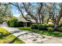 A beautiful home featuring a long driveway, mature trees, lush greenery, and manicured landscaping at 3614 Twisted Oak Ct, Lake Wales, FL 33898