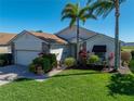 Charming home featuring a brick driveway, well-manicured lawn, and lush landscaping with tropical palm trees at 4115 Muirfield Loop, Lake Wales, FL 33859