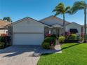 Charming home featuring a brick driveway, well-manicured lawn, and lush landscaping with tropical palm trees at 4115 Muirfield Loop, Lake Wales, FL 33859