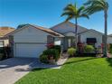 Charming home featuring a brick driveway, well-manicured lawn, and lush landscaping with tropical palm trees at 4115 Muirfield Loop, Lake Wales, FL 33859