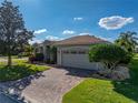 Charming home with a well-manicured lawn, mature landscaping and brick-paved driveway leading to the attached two-car garage at 4232 Roebelenii Dr, Lake Wales, FL 33859