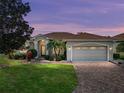 Charming home with a well-manicured lawn, mature landscaping and brick-paved driveway at sunset at 4232 Roebelenii Dr, Lake Wales, FL 33859