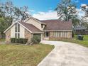 Charming home with driveway, brick and siding facade, and mature trees in the yard at 4765 Lantern Ct, Orlando, FL 32808