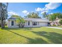 A single-story home boasts a well-kept lawn and mature trees against a bright blue sky at 5115 Woodgreen Ln, Lakeland, FL 33811