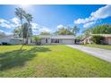 Inviting single-story home with lush green lawn and mature trees on a sunny day at 5115 Woodgreen Ln, Lakeland, FL 33811