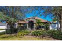 Charming single-story home featuring stone accents, a screened entrance, a well-manicured lawn, and mature palm trees at 625 Hatchwood Dr, Haines City, FL 33844