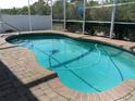 A serene in-ground pool with brick trim is surrounded by a screened enclosure, offering a private outdoor oasis at 100 Heatherwood Blvd, Lake Wales, FL 33859