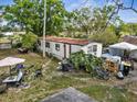 Mobile home surrounded by miscellaneous items and overgrown plants at 215 10Th Wahneta W St, Winter Haven, FL 33880