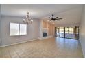 Open living room with tile floors, large windows, a decorative chandelier, and a cozy fireplace at 4174 Pirates Lndg, Winter Haven, FL 33884