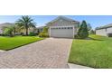 Paver driveway leading to a well-maintained home with lush landscaping at 462 Lake View Way, Auburndale, FL 33823