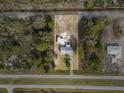 An aerial view showing the home and shed surrounded by treed lot and nearby road at 6261 Red Grange Blvd, Indian Lake Estates, FL 33855