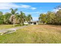 Expansive front lawn showcases this lovely single-story home with a long driveway, mature trees and blue skies at 6261 Red Grange Blvd, Indian Lake Estates, FL 33855