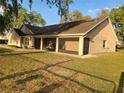 Tan single Gathering home featuring an attached garage and a covered and screened-in porch, perfect for outdoor enjoyment at 700 E Park Rd, Haines City, FL 33844