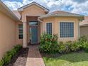Inviting front door with decorative glass and colorful landscaping, complemented by brick walkway at 1124 Sawgrass Dr, Winter Haven, FL 33884