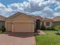 Charming single-Gathering home featuring a manicured lawn, brick driveway, and attached two-car garage at 1124 Sawgrass Dr, Winter Haven, FL 33884