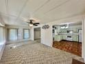 Bright living room open to kitchen with ceiling fan and natural light from large windows at 114 Jana Cir, Auburndale, FL 33823