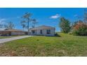 A single-story home with a lush green lawn and mature trees under a clear blue sky at 225 Babson Dr, Babson Park, FL 33827