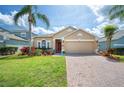 Charming single-Gathering home with a well-manicured lawn, beautiful landscaping, and a brick paver driveway at 225 Highgate Park Blvd, Davenport, FL 33897